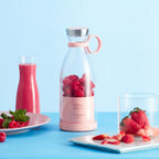 Pink juice bottle with raspberries, pink smoothie, and strawberries on a blue background