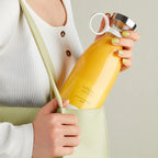 Person holding a yellow bottle labeled 'Fresh Juice' against a neutral background