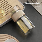 Glass tea infuser with gold accents on a dark surface, labeled 'Champagne Gold'.