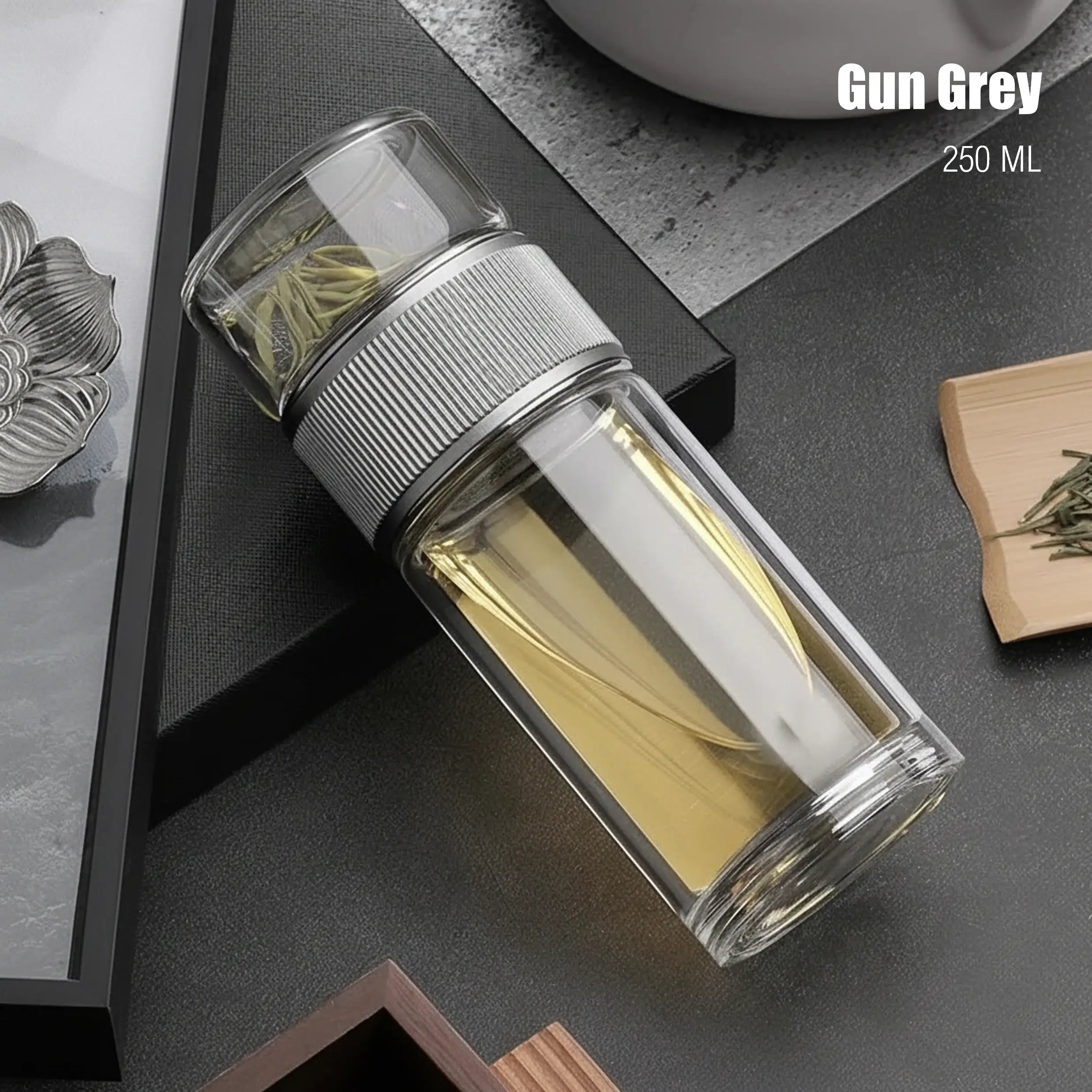 Clear glass bottle with silver lid on a dark surface, labeled 'Gun Grey 250 ML'.