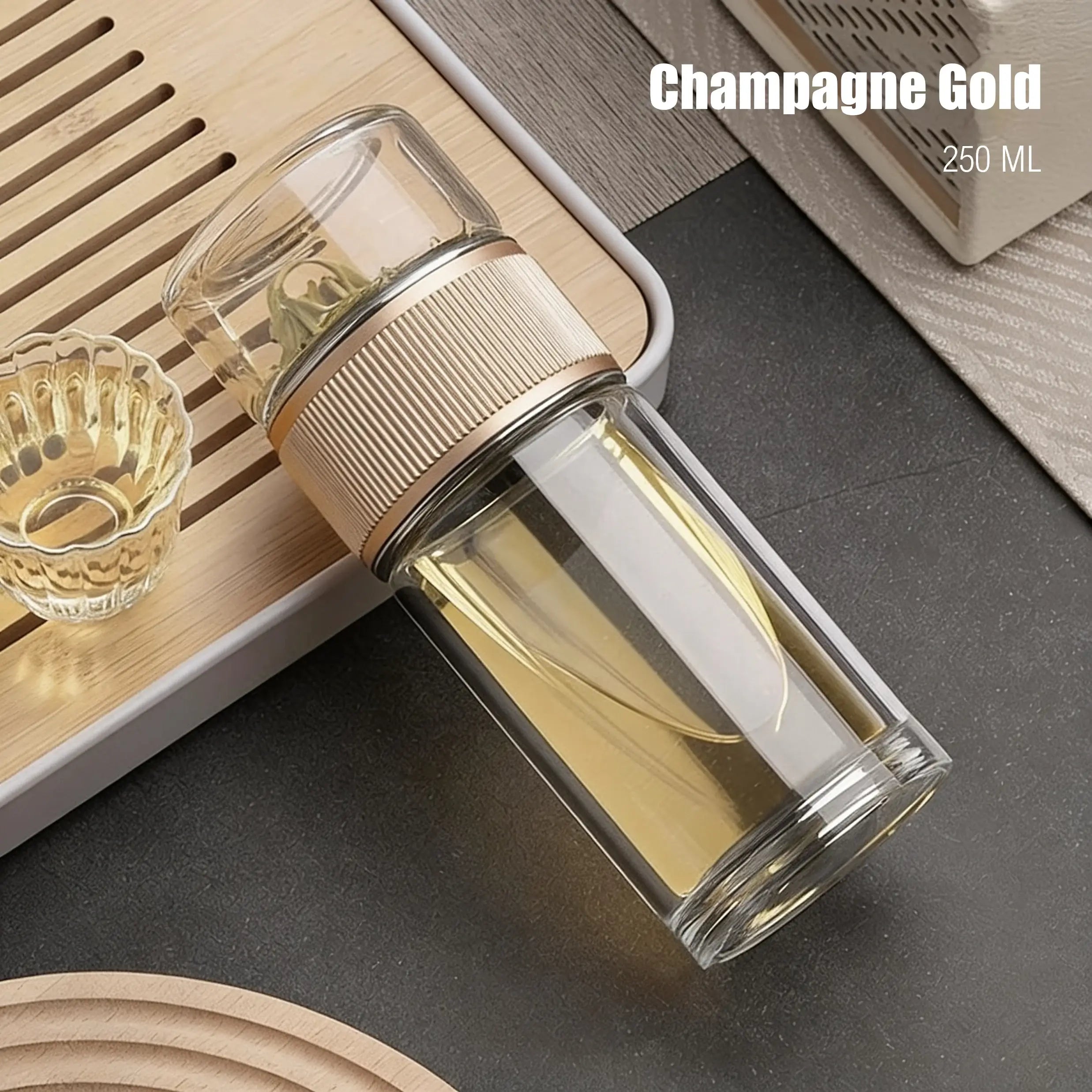 Clear glass bottle with gold cap on a dark surface, labeled 'Champagne Gold 250 ML'.