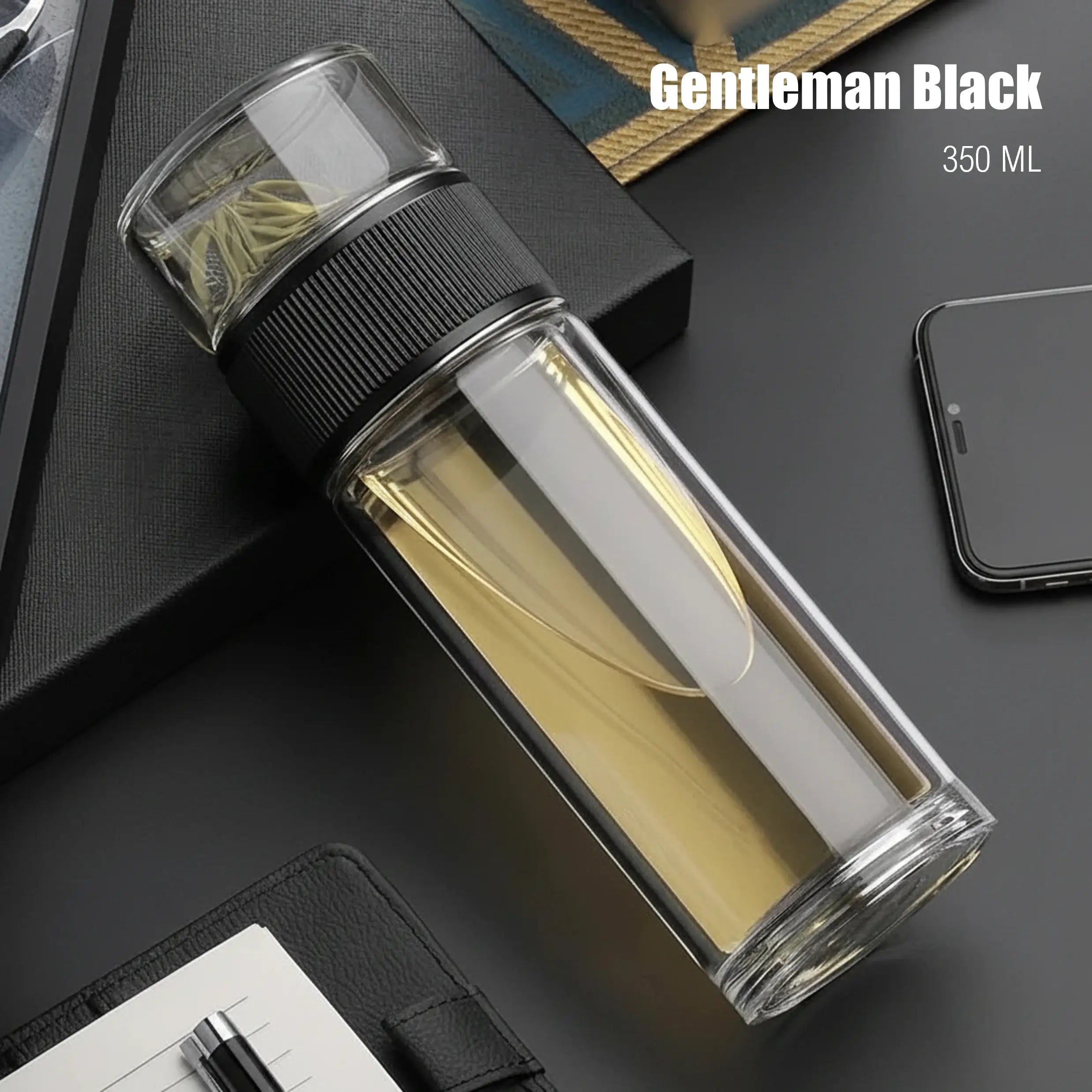 Glass water bottle with black lid on a dark surface, labeled 'Gentleman Black' and '350 ML'.