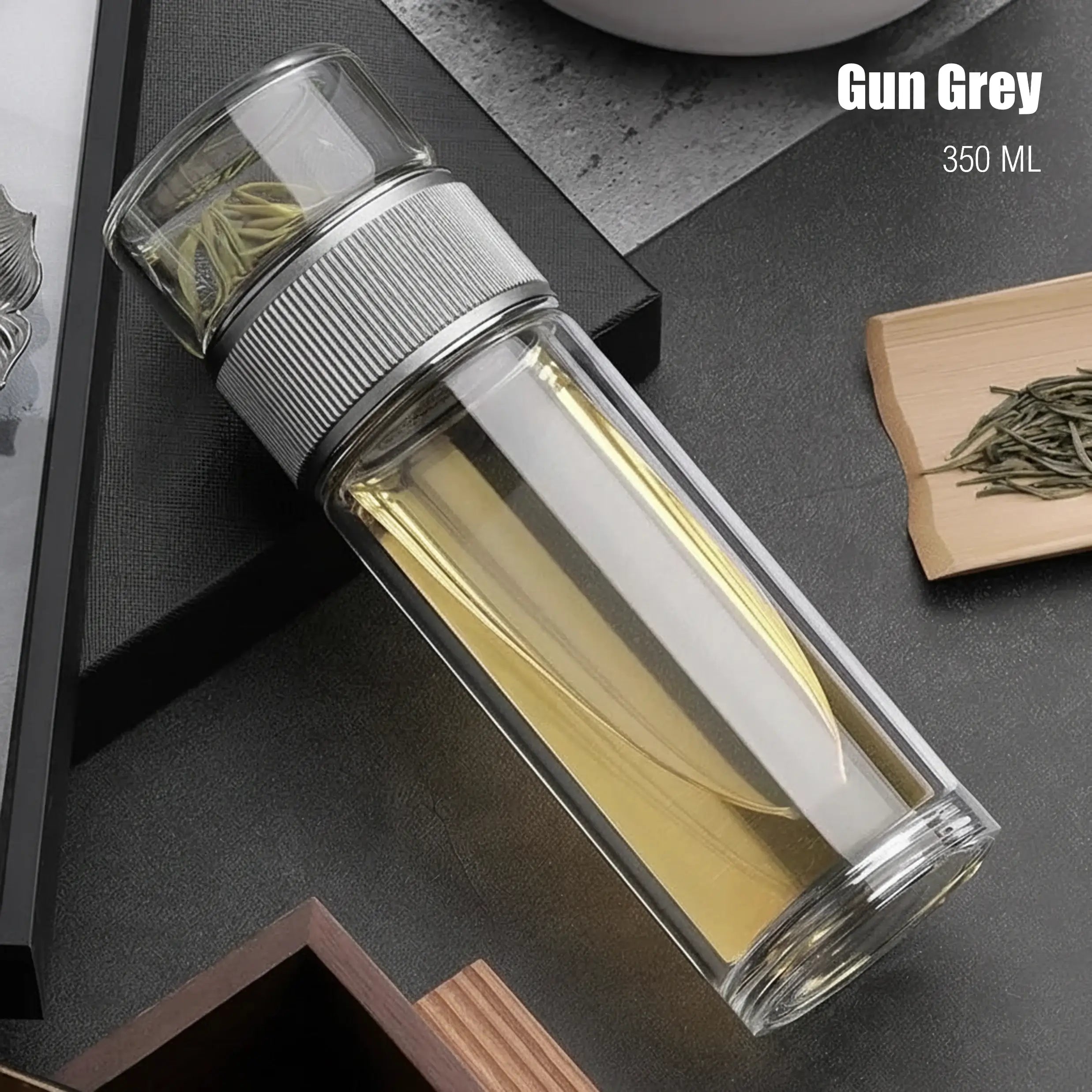 Clear glass bottle with silver lid on a dark surface, labeled 'Gun Grey 350 ML'.